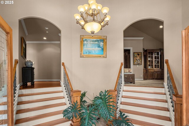 stairway featuring crown molding, hardwood / wood-style flooring, and an inviting chandelier