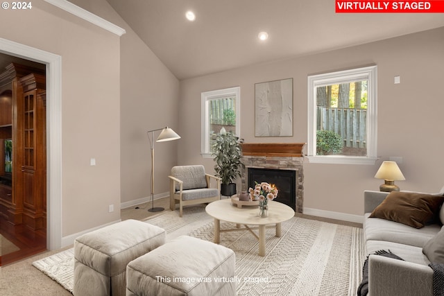 living room with vaulted ceiling and a stone fireplace