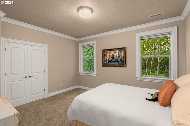 bedroom with a textured ceiling, crown molding, carpet flooring, and a closet