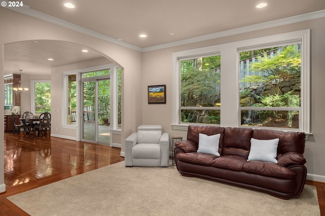 living room featuring hardwood / wood-style flooring, ornamental molding, and an inviting chandelier