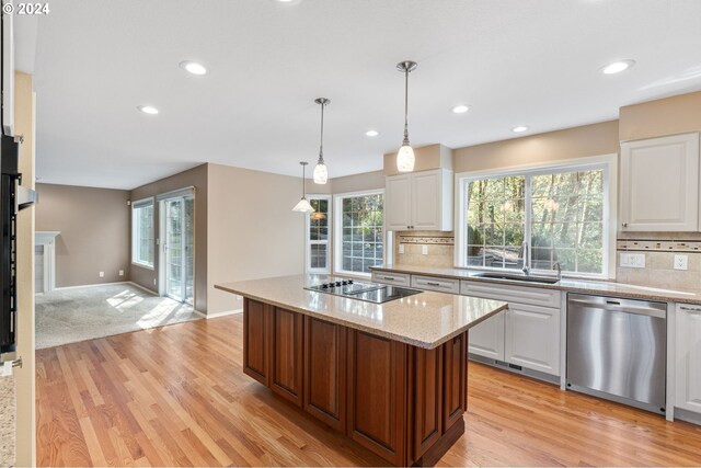 kitchen featuring a kitchen island, light stone countertops, stainless steel dishwasher, black electric stovetop, and white cabinets