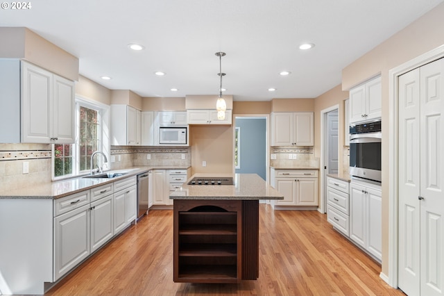 kitchen with appliances with stainless steel finishes, light hardwood / wood-style floors, a center island, sink, and white cabinetry