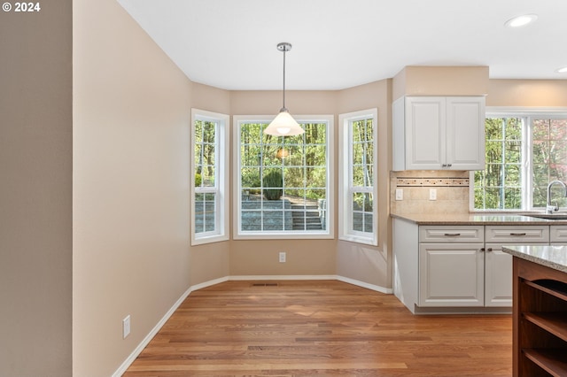 kitchen with light stone counters, white cabinetry, and light hardwood / wood-style floors