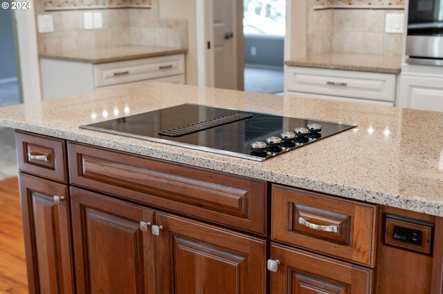 kitchen featuring black electric cooktop, light stone counters, and stainless steel oven