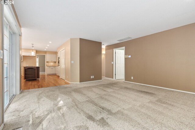 unfurnished living room with light carpet and a healthy amount of sunlight