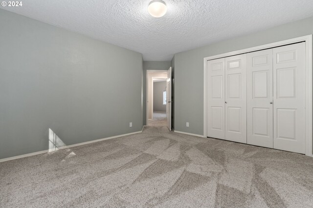 unfurnished bedroom with a textured ceiling, a closet, and light carpet