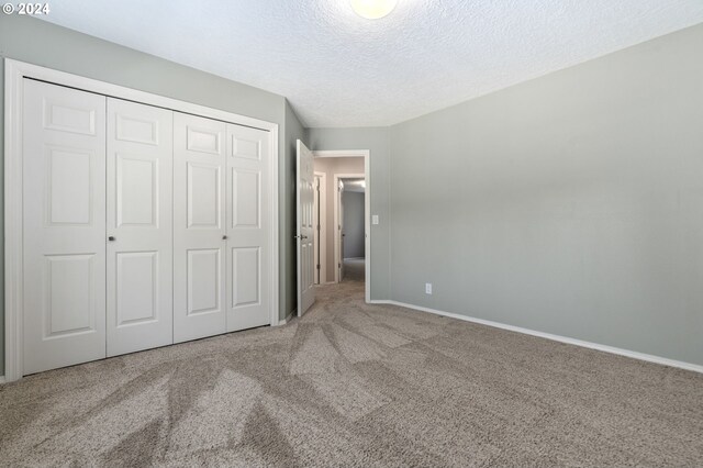 unfurnished bedroom with a textured ceiling, carpet flooring, and a closet