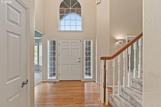 entrance foyer featuring a towering ceiling and light hardwood / wood-style flooring