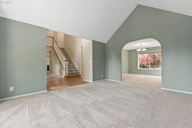 unfurnished living room with high vaulted ceiling, light hardwood / wood-style flooring, and a notable chandelier