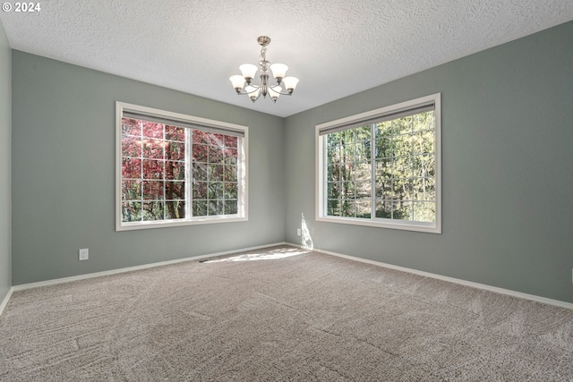 carpeted empty room featuring an inviting chandelier and a textured ceiling