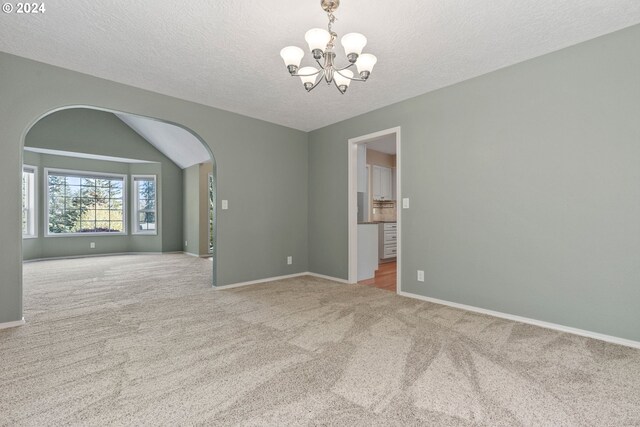 unfurnished room with light carpet, vaulted ceiling, a textured ceiling, and a chandelier