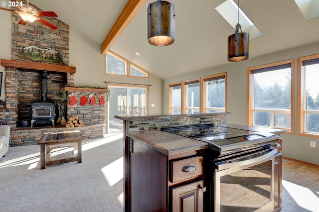 kitchen featuring a wood stove, stainless steel electric stove, ceiling fan, decorative light fixtures, and light colored carpet