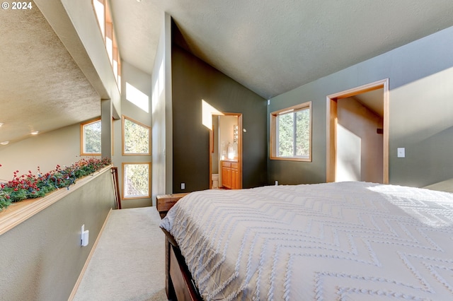 bedroom featuring a textured ceiling, carpet floors, ensuite bathroom, and lofted ceiling