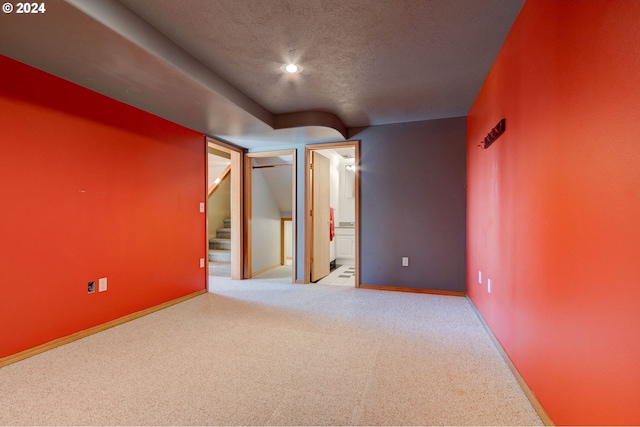 basement featuring a textured ceiling and light carpet