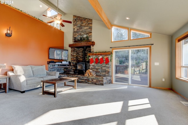 living room with a wood stove, ceiling fan, carpet, and high vaulted ceiling