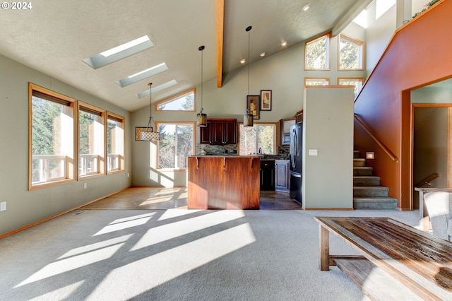 carpeted living room featuring a skylight, a wealth of natural light, beamed ceiling, and high vaulted ceiling