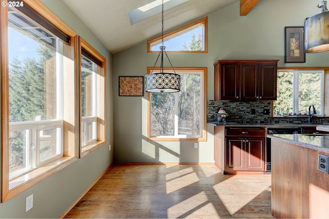 kitchen featuring pendant lighting, dishwasher, a skylight, decorative backsplash, and light wood-type flooring