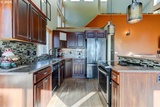 kitchen featuring backsplash, sink, hanging light fixtures, light hardwood / wood-style flooring, and appliances with stainless steel finishes