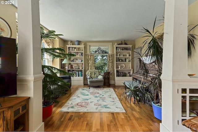 sitting room with a textured ceiling, decorative columns, and hardwood / wood-style floors