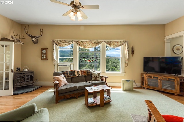 living room with ceiling fan, cooling unit, hardwood / wood-style floors, and a wood stove