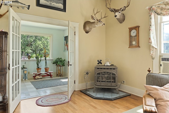 interior space with a healthy amount of sunlight, french doors, a wood stove, and wood finished floors