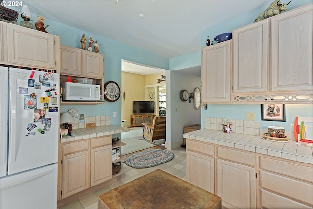 kitchen featuring light brown cabinetry, white appliances, and tile counters