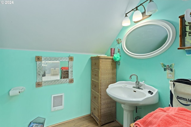 bathroom featuring wood-type flooring and vaulted ceiling