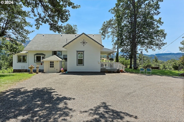 view of front of house featuring a porch, a mountain view, and gravel driveway