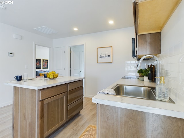 kitchen featuring light hardwood / wood-style flooring, decorative backsplash, a center island, and sink