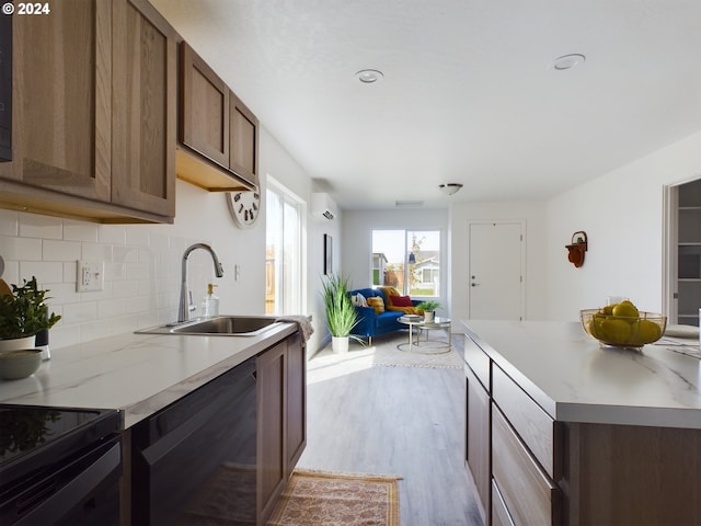 kitchen with decorative backsplash, black dishwasher, a wall mounted air conditioner, light hardwood / wood-style floors, and sink