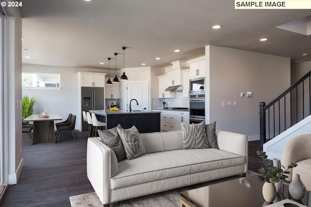 living room with a textured ceiling, sink, and dark wood-type flooring