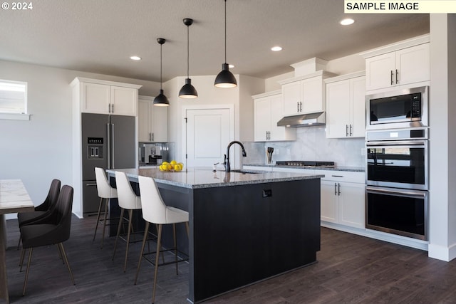 kitchen featuring white cabinets, pendant lighting, a center island with sink, and stainless steel appliances