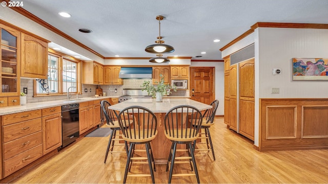 kitchen featuring appliances with stainless steel finishes, hanging light fixtures, a kitchen island, sink, and wall chimney range hood