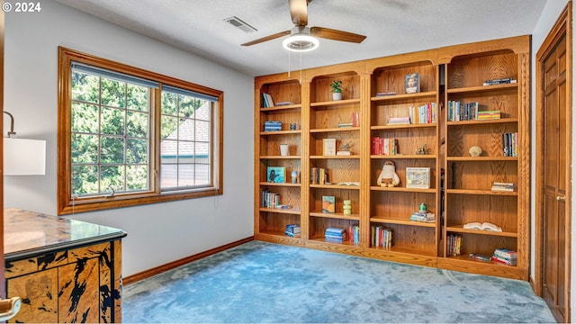 interior space with a textured ceiling, ceiling fan, and light carpet