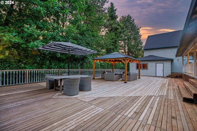 deck at dusk featuring a gazebo and outdoor lounge area