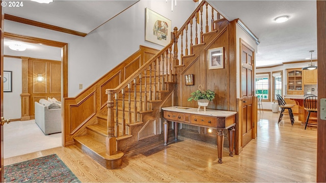 stairway with crown molding and wood-type flooring