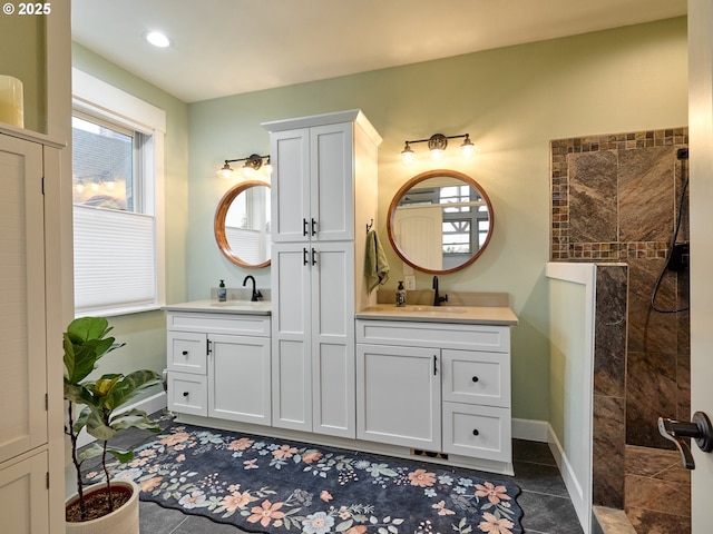 bathroom featuring tile patterned flooring, a tile shower, and vanity