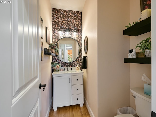 bathroom with toilet, vanity, and hardwood / wood-style floors