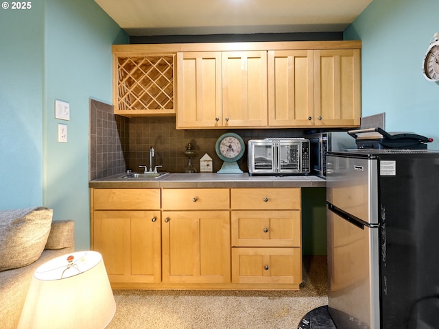 kitchen with sink, light brown cabinetry, stainless steel fridge, tasteful backsplash, and stainless steel counters