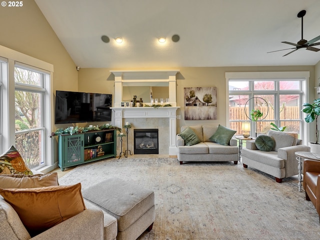 living room featuring a tile fireplace, ceiling fan, vaulted ceiling, and plenty of natural light