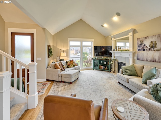 living room featuring a fireplace, vaulted ceiling, and light hardwood / wood-style flooring