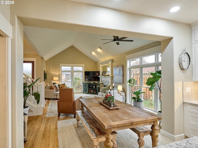 dining room featuring ceiling fan, light wood-type flooring, and vaulted ceiling