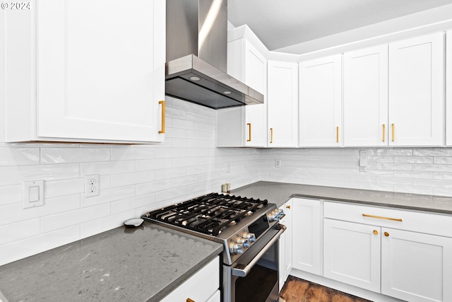 kitchen featuring wall chimney range hood, gas stove, white cabinets, hardwood / wood-style floors, and backsplash