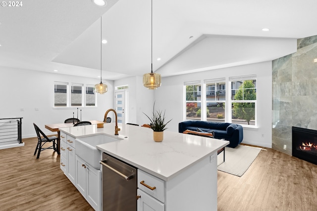 kitchen with lofted ceiling, an island with sink, white cabinetry, dishwasher, and pendant lighting