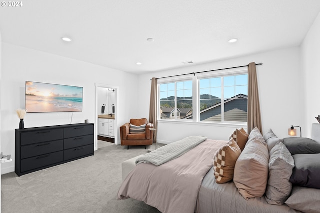 bedroom with ensuite bath and light colored carpet