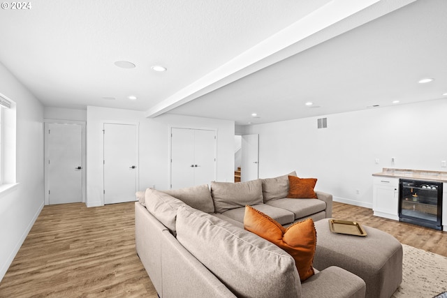 living room with light hardwood / wood-style flooring, bar area, and beverage cooler