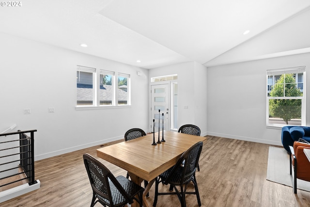 dining room with a wealth of natural light, vaulted ceiling, and light hardwood / wood-style flooring