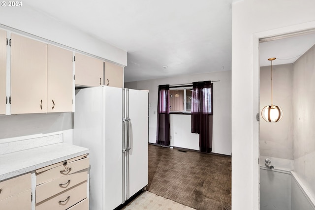 kitchen featuring cream cabinetry, white refrigerator, and decorative light fixtures