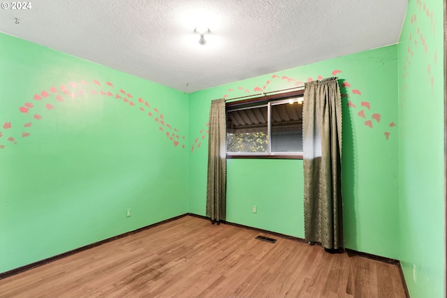 spare room with a textured ceiling and light wood-type flooring