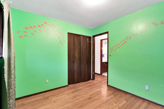 unfurnished bedroom featuring light hardwood / wood-style floors, a textured ceiling, and a closet